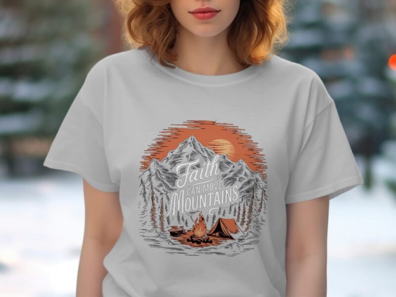 A woman wears a light gray t-shirt featuring a mountain graphic and the text "Faith can move Mountains."