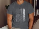 Man wearing a gray t-shirt with a distressed American flag design, sitting in a cozy indoor setting.