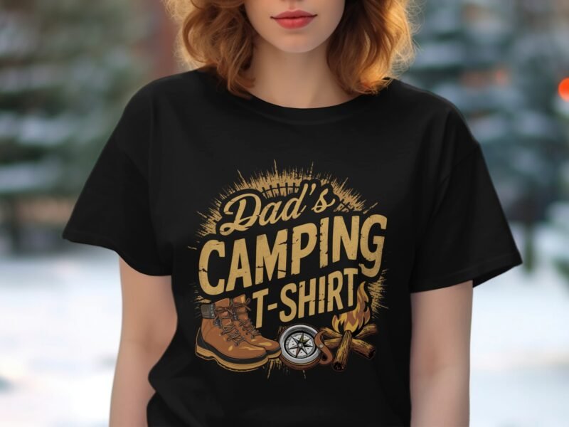 A woman wearing a black t-shirt featuring the text "Dad's Camping T-Shirt" with camping graphics in a blurred outdoor background.