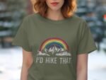 A woman in an olive green t-shirt with a rainbow and mountains graphic, text reads "I’d hike that."