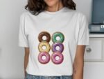 Woman wearing a white t-shirt featuring a graphic of six colorful donuts arranged in two columns.