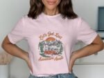 A woman wearing a pink t-shirt with "Let's Get Lost" graphic, featuring a van, mountains, and trees.