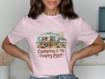 Woman wearing a pink t-shirt with a vintage camper graphic and the text "Camping is my happy place."