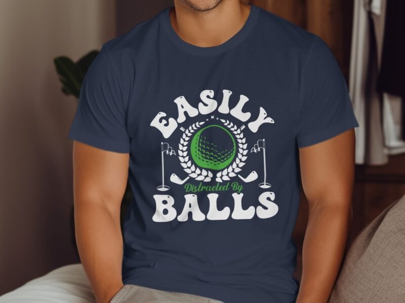 A man wearing a navy t-shirt with the text "Easily Distracted By Balls" and golf-themed graphics.