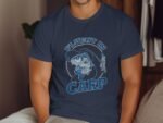 A person wears a navy blue t-shirt featuring a graphic of a carp and the text "Fluent in Carp."