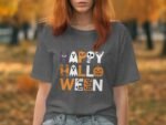 Woman wearing a gray t-shirt featuring "Happy Halloween" in colorful, festive letters with spooky graphics.