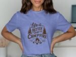 Woman in a blue t-shirt with the phrase "Life is better around the campfire," featuring trees and a campfire graphic.