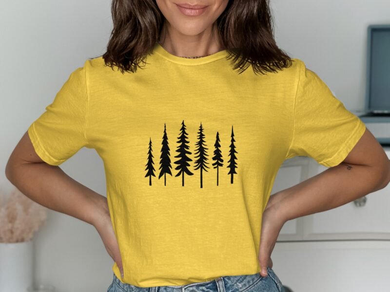 A woman wearing a yellow t-shirt with a black tree graphic, posing with her hands on her hips.