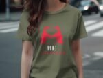 A woman in an olive green t-shirt featuring red birds forming a heart and the text "BE YOUTIFUL" below.