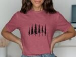 Woman wearing a pink t-shirt with a black pine tree graphic, smiling against a neutral background.