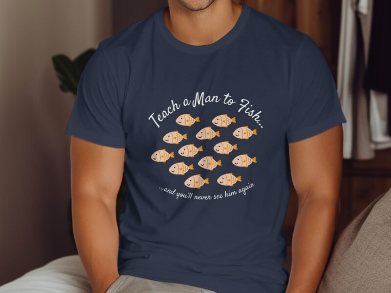 A person in a navy blue shirt with a humorous fish-themed design, text reads "Teach a Man to Fish..."