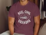 A man wears a maroon t-shirt with the text "REEL COOL GRANDPA" and a fish graphic, sitting in a cozy room.
