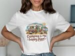 A woman in a white t-shirt featuring a colorful camping graphic with text "Camping is my happy place."