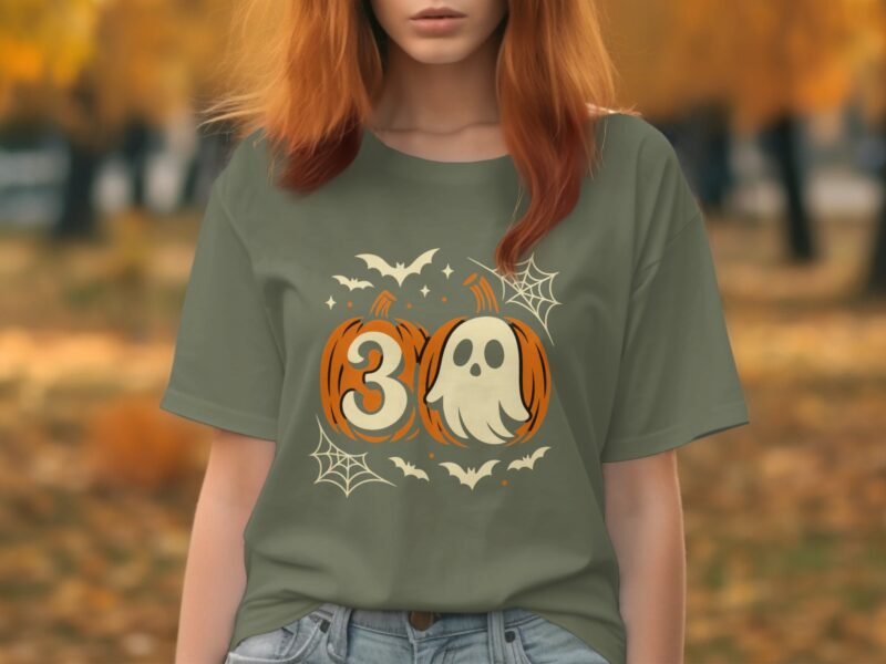 A young woman in a green Halloween-themed t-shirt featuring pumpkins, a ghost, bats, and the number 30.
