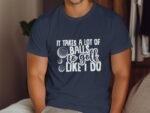 A person wearing a navy blue t-shirt with the humorous phrase "It takes a lot of balls to golf like I do."