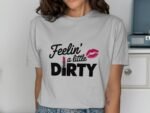 A woman in a gray t-shirt with the text "Feelin' a little DIRTY" and a pink lipstick graphic, smiling at the camera.