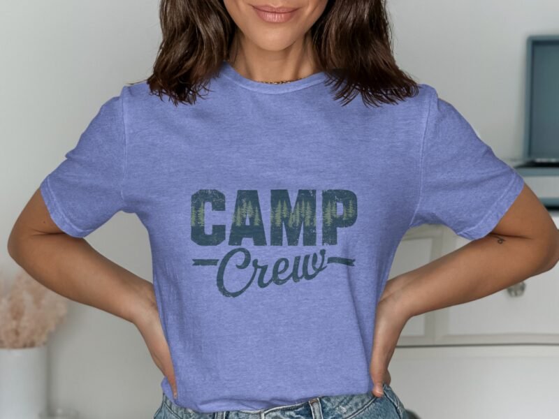 Woman smiling while wearing a lavender t-shirt with "CAMP Crew" graphic in dark green lettering.