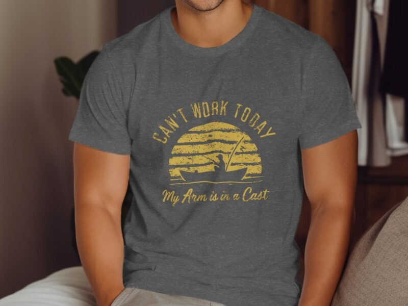A man wearing a gray t-shirt with the text "Can't Work Today, My Arm is in a Cast" and a graphic design of a sunset.