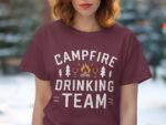 A woman wearing a maroon t-shirt with "Campfire Drinking Team" text and illustrations of trees, fire, and drinks.