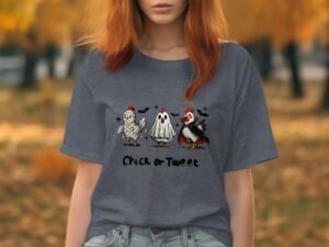 A woman with red hair wears a gray t-shirt featuring cartoon chickens and a ghost, with the text "Chick or Tweet."
