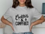 A woman in a gray t-shirt with the text "Cocktails & Campfires" displayed in bold black lettering.