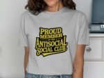 A woman wearing a light gray t-shirt with the text "PROUD MEMBER OF THE ANTISOCIAL SOCIAL CLUB" in bold yellow letters.
