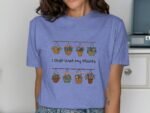 A person wearing a blue shirt with "I Just Wet My Plants" and colorful hanging flower baskets graphic.