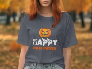 A woman in a gray Halloween-themed t-shirt with a pumpkin graphic stands outdoors in a fall setting.