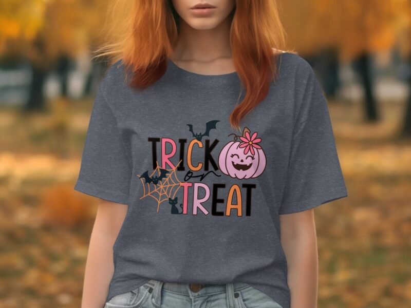 Woman wearing a gray t-shirt with "TRICK or TREAT" graphic, surrounded by autumn foliage.