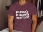 A person wearing a maroon t-shirt with the text "WEAPONS OF GRASS DESTRUCTION" and a golf bag graphic.
