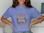 Woman wearing a blue t-shirt with a retro camper van graphic, mountains, and text: "Let's Get Lost Adventure Awaits."