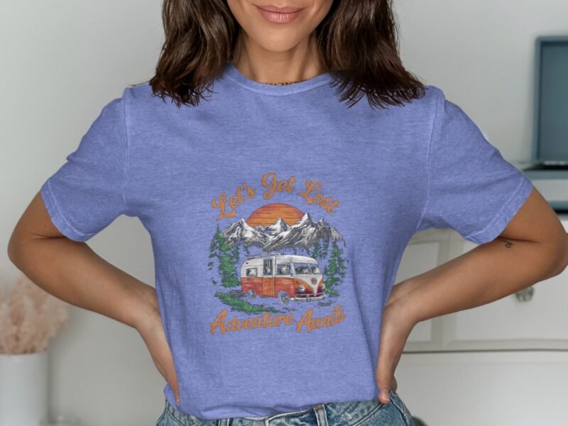Woman wearing a blue t-shirt with a retro camper van graphic, mountains, and text: "Let's Get Lost Adventure Awaits."