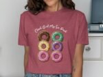 A woman in a maroon t-shirt with a graphic of six colorful donuts and the text "Check Out My Six Pack."