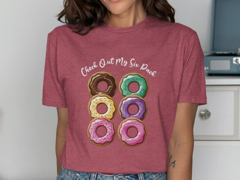 A woman in a maroon t-shirt with a graphic of six colorful donuts and the text "Check Out My Six Pack."