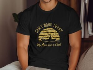 A person wearing a black t-shirt with the text "Can't Work Today My Arm is in a Cast" and a graphic of a boat.