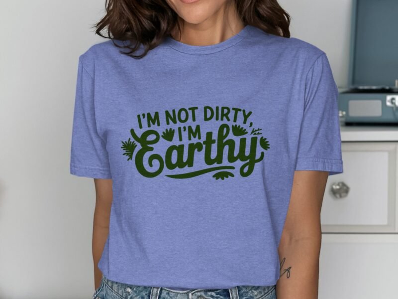 Woman wearing a light blue t-shirt with green text saying "I'm not dirty, I'm Earthy," displaying a casual style.