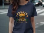 A person wearing a navy blue t-shirt featuring a burger graphic with the text "BURGER STORAGE FACILITY" in bold.