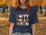 A person wears a navy t-shirt with "HAPPY HALLOWEEN" in colorful, spooky-themed lettering against a fall background.