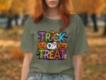 Person wearing a grey t-shirt with "TRICK OR TREAT" graphic, featuring pumpkins and a ghost, in a fall outdoor setting.