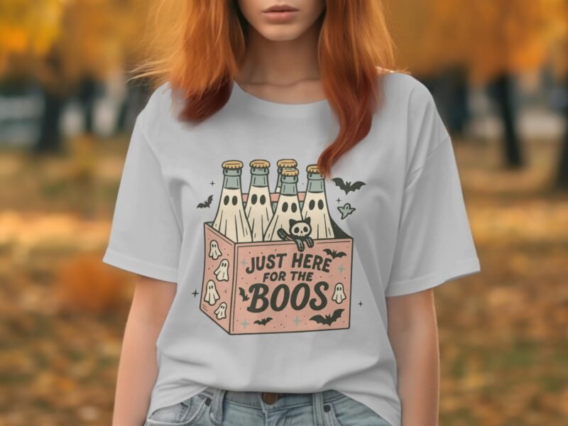 A young woman with long red hair wearing a gray t-shirt featuring a playful graphic with bottles and Halloween elements.
