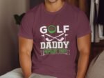 A man wearing a maroon t-shirt with "GOLF DADDY MEMBERS ONLY" and graphics of golf clubs and a golf ball.