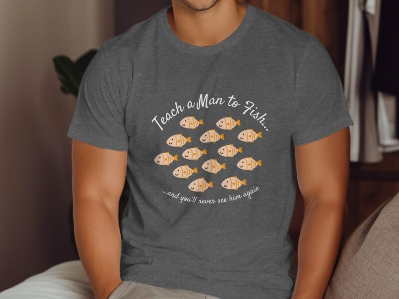 A person wearing a gray t-shirt with the text "Teach a Man to Fish..." and illustrations of orange fish.