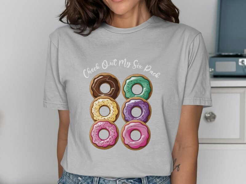 Woman wearing a gray t-shirt with a colorful donut graphic and text saying "Check Out My Six Pack."