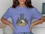 Woman wearing a light blue t-shirt with a "Camp Crew" graphic featuring a tent and pine trees.