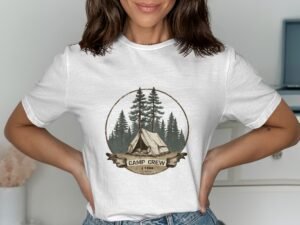 Woman in a white t-shirt featuring a camping design with trees and a tent, smiling against a light background.