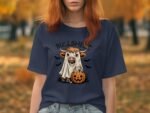 A woman with red hair wears a navy t-shirt featuring a cow in a ghost costume with a pumpkin, surrounded by bats.