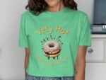 Woman wearing a green t-shirt featuring a cartoon donut and the text "Very Hot, Handle With Care."