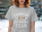 Woman wearing a gray t-shirt with the text "CAMPFIRE DRINKING TEAM" surrounded by fire and tree graphics.