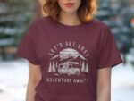 A woman in a maroon t-shirt with a camping graphic that reads "Let's Get Lost Adventure Awaits." Background is blurred trees.