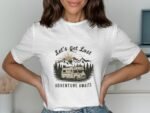 A woman poses wearing a white t-shirt with a camper van graphic and text reading "Let's Get Lost Adventure Awaits."